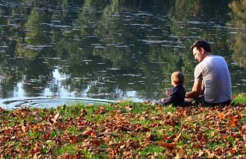 apa és gyermeke ül a folyóparton